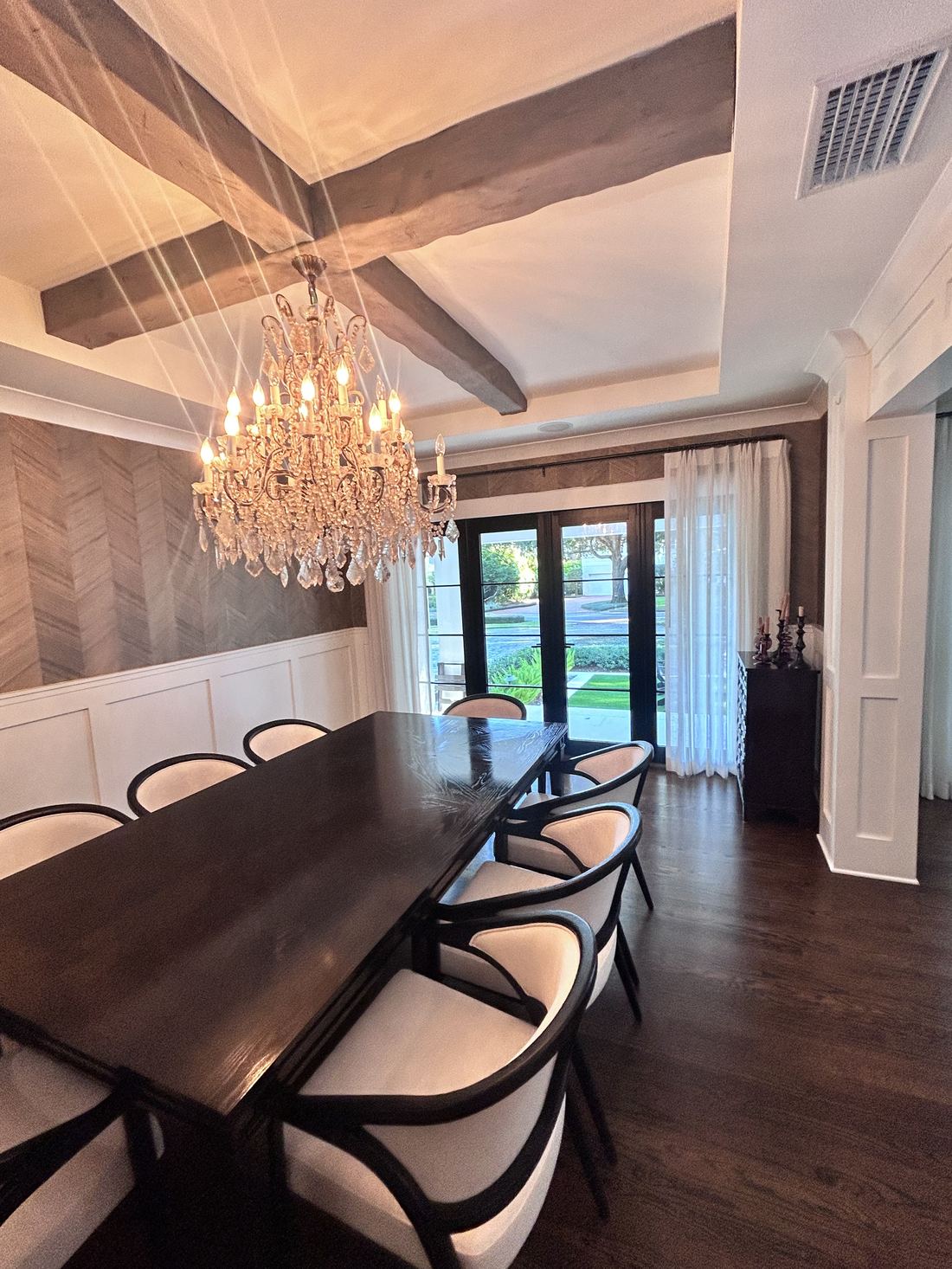 Crystal chandelier installed in a formal dining room with wood beam ceiling