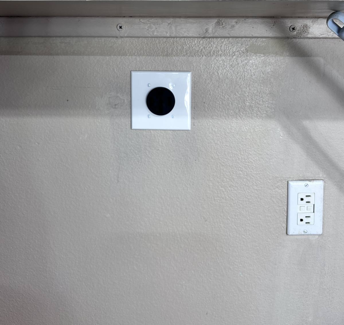 Dedicated 240-volt EV charging receptacle installed in a garage next to an existing GFCI outlet