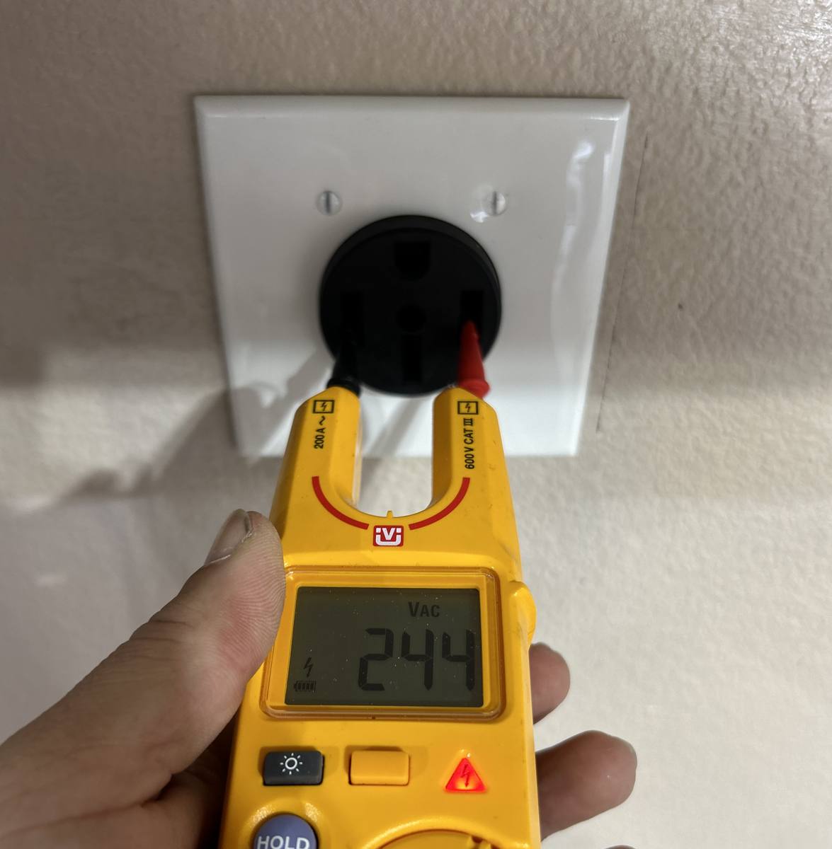 Electrician testing voltage at a newly installed NEMA 14-50 EV charging receptacle on a 240-volt circuit