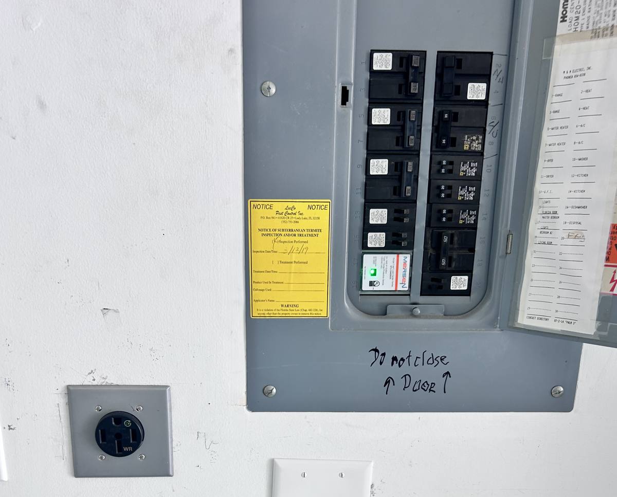 Residential electrical panel with breakers, surge protective device, and a dedicated 50-amp receptacle nearby