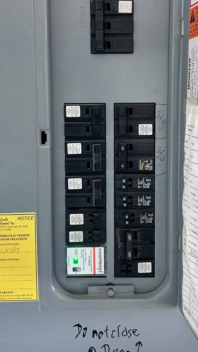 Interior of a residential breaker panel showing labeled circuits and an installed surge protective device